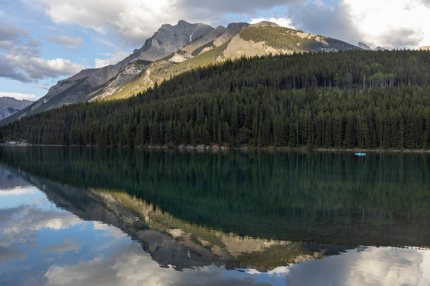 A serene mountain landscape is reflected in a tranquil lake surrounded by lush forests.